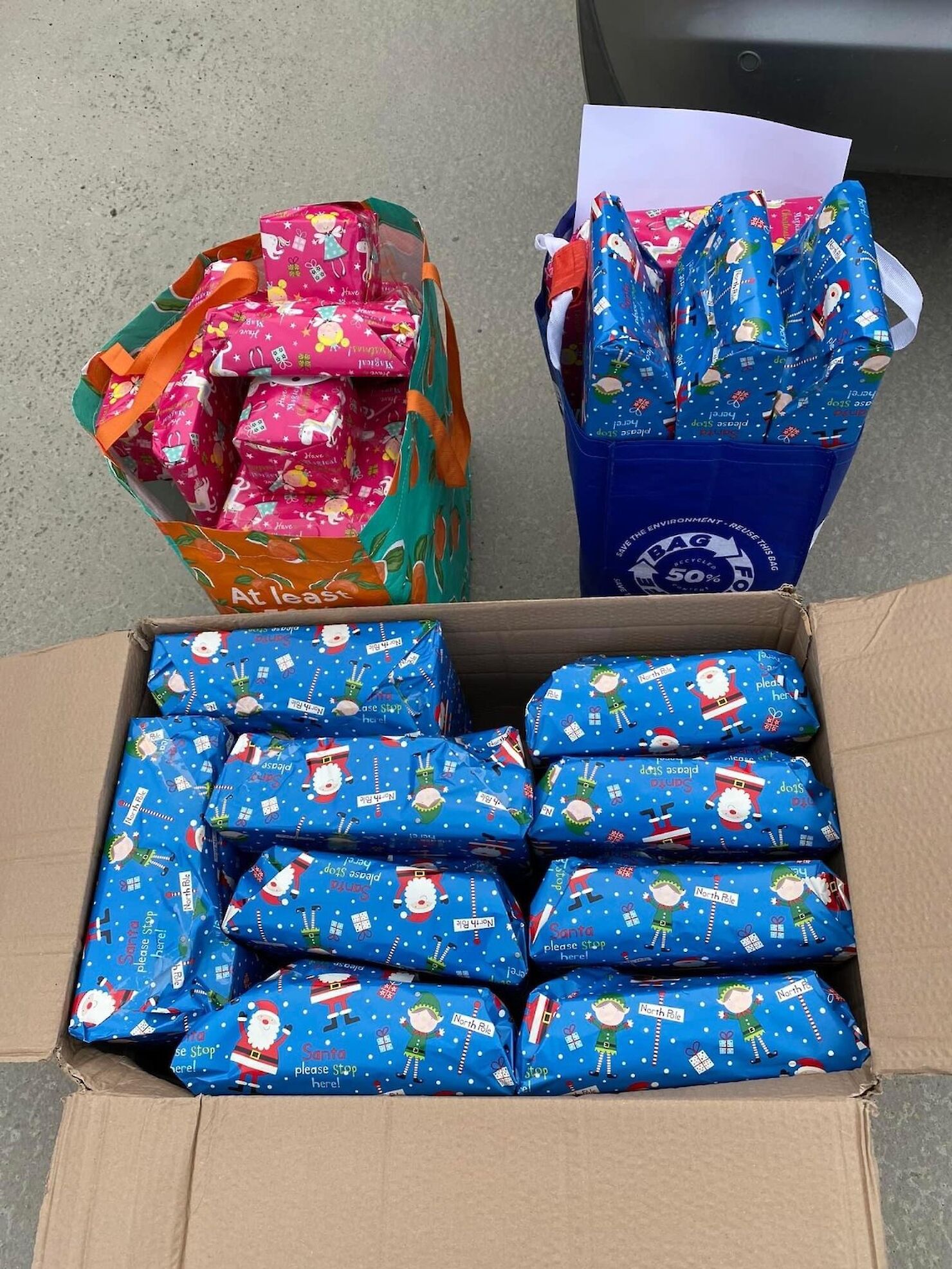A box and two bags filled with Christmas presents wrapped and ready to go to Women&rsquo;s Aid